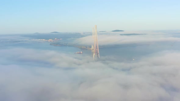 The Pylons of the Giant Cablestayed Bridge Rise Above the Seaside Morning Fog alt