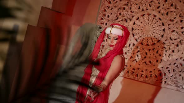 a Woman in a Turban a Red Scarf and a Sequined Dress Dances in the Sunset Light alt