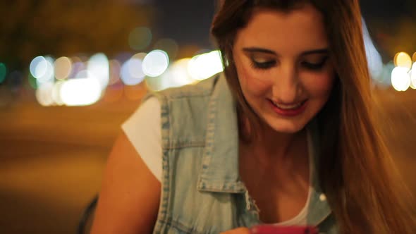 Teenage girl using smartphone outdoors at night