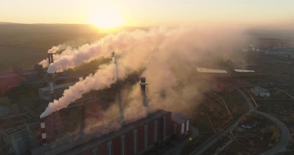 Smoking chimneys of industrial buildings complex at sunset. Heavy industry from above.  alt