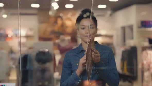 Young African American Woman Turning a Sign From Closed to Open on the Door of a Women's Brand alt
