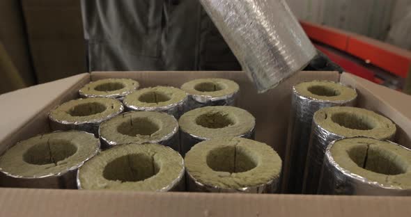 Worker Folds Made Insulation for Pipes Into a Large Box