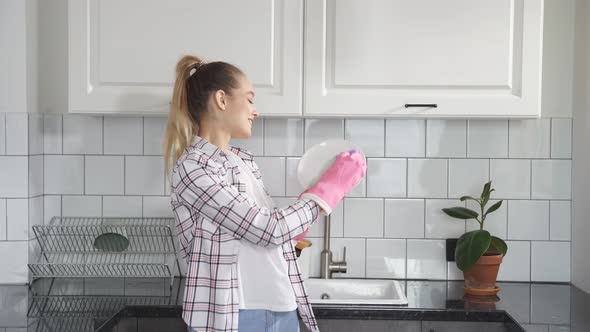Attractive Young Caucasian Woman Washing Dishes at Kitchen Sink While Doing Cleaning at Home at