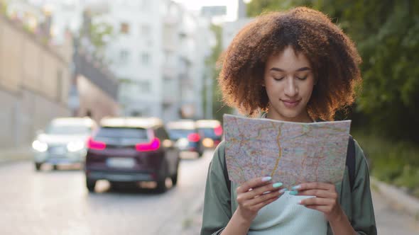 Happy Smiling Attractive African American Woman Tourist with Paper Map in Hands on Summer Sunny Day alt