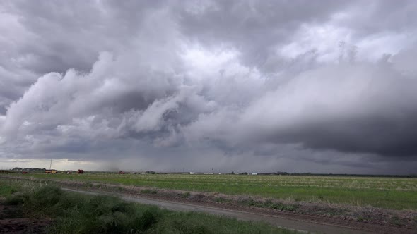 Severe storm clouds rolling in the sky as tornado forms in the background alt