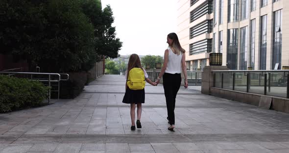 Happy Little Caucasian Blonde Girl Seven Years Old in Uniform with Yellow Backpack Going Back to alt