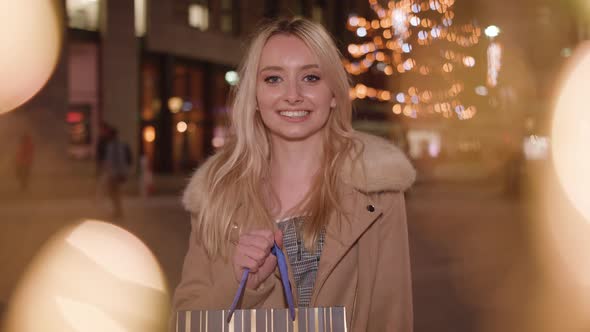 young attractive woman shows off her recent purchase from shopping trip and smiles alt