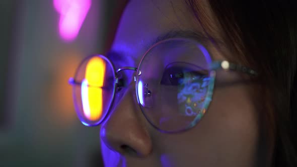 Focus eyes glasses of asian woman playing online computer video game with lighting effect.