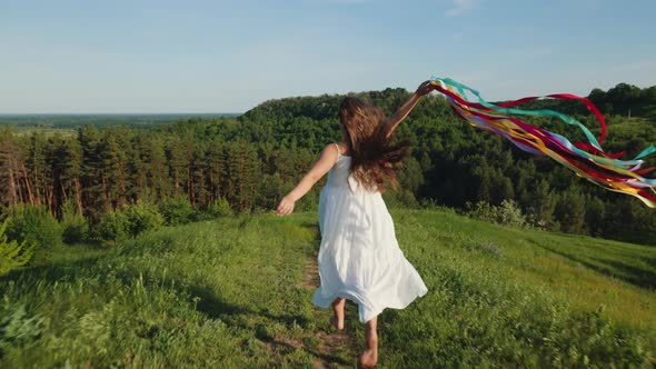 Girl with Rainbow Ribbons Running Down the Mountain