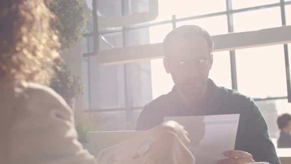 Businessman and Businesswoman Analyzing Documents alt