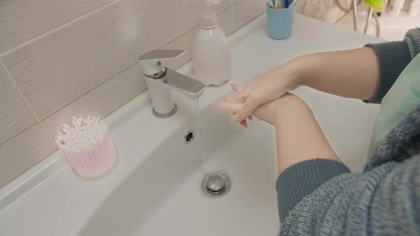 Woman Washes Her Hands Thoroughly in the Bathroom