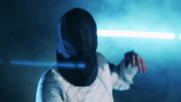 Fencer in a Protection Mask is Practicing with a Foil alt