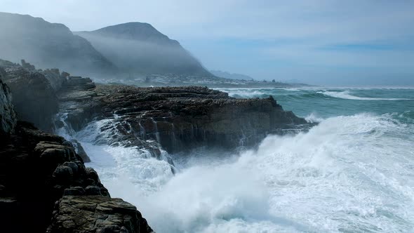 Huge wave making a big splash as it crashes into rocks on rocky coastline, Hermanus alt