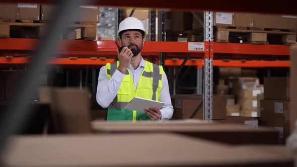 Engineer Communicating By Radio Set in Warehouse alt