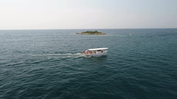 Small Boat with passengers sailing near tiny island in Adriatic Sea, Croatia alt