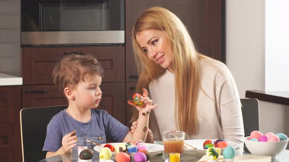Young Woman with Her Adorable Little Son Making Handmade Decorations for Easter Holiday alt