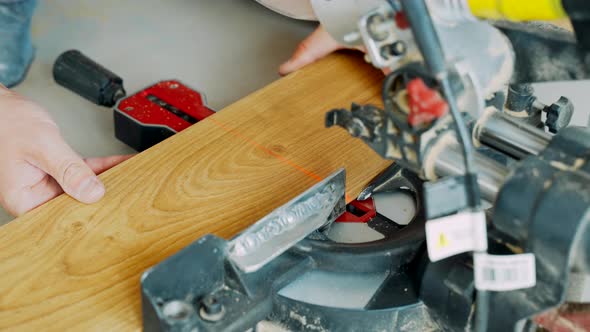 A Worker Cuts Off a Laminated Board with an Electric Miter Saw. Laying the Floor Covering. alt