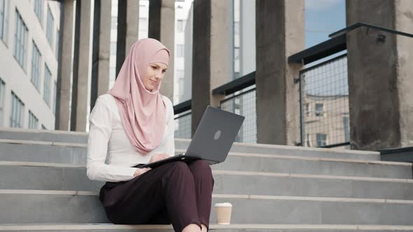 Portrait of Attractive Arabian Woman in Elegant Clothes and Hijab Sitting on alt