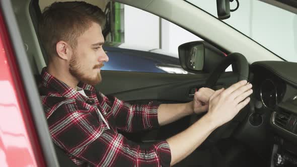 Young Man Examining Interior of a New Car at the Dealership Salon alt