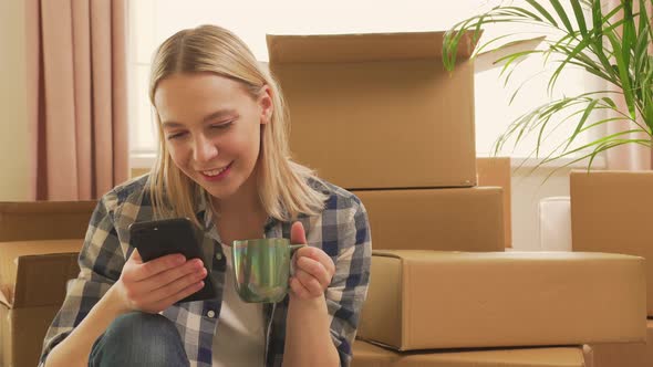 The Woman Took a Break During the Move Sits on the Floor and Drinks Tea