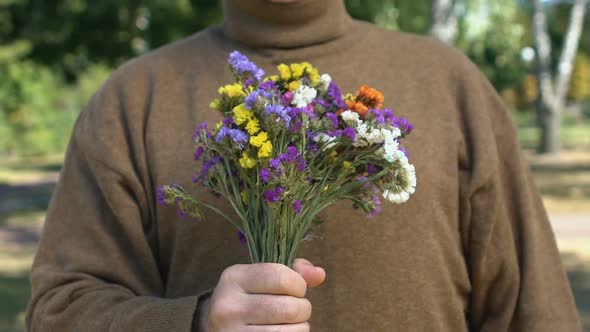 Senior Male Pensioner Stretching Out Hand With Wildflowers, Date Present, Love