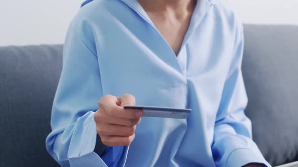 Young Asia lady using laptop, credit card buy and purchase e-commerce internet in living room
