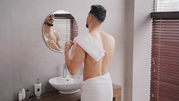 Naked Arabian Arab Indian Bearded Man Washing Face Looking in Mirror Wiping Wet Face with White alt