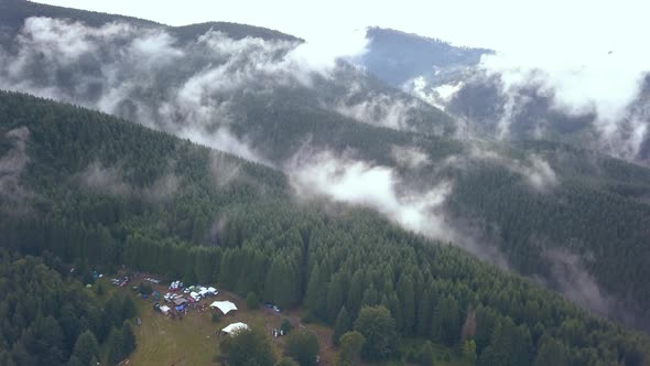 Aerial Drone Shot of a Festival Campground Punching in to Reveal the Vastness of the Romania Mountai alt