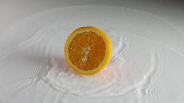 Orange Falls on the Water Surface and Breaks in Half
