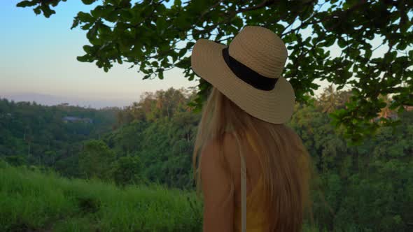 A Young Woman in a Yellow Dress Walking at the Campuhan Ridge Walk or Painter's Walkway in Ubud alt