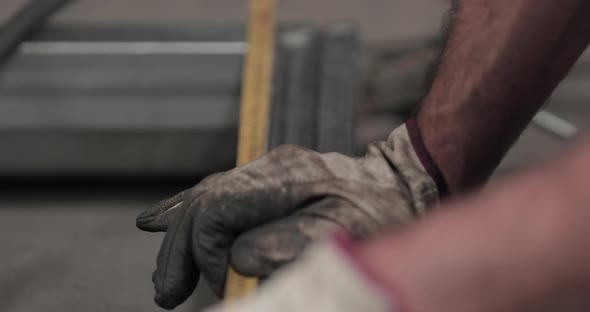 Hands With Dirty Gloves Measuring Tubular Frame With A Tape Measure - rack focus, slow motion alt