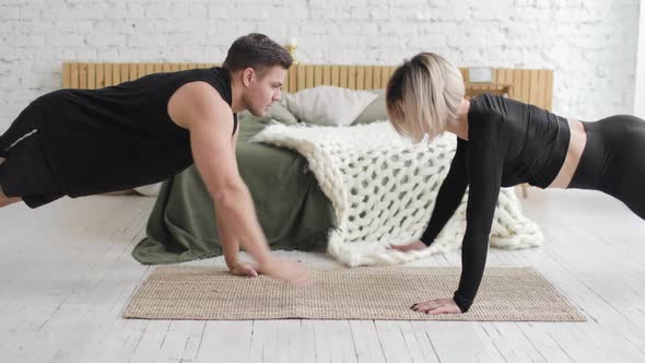 Fitness Couple Doing Push Up Exercises and Giving Each Other High Five at Home