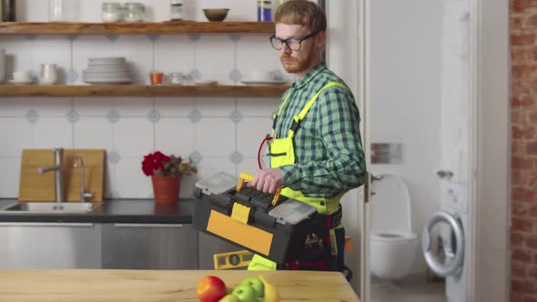 Professional Repairman Walking in Kitchen with Toolbox alt