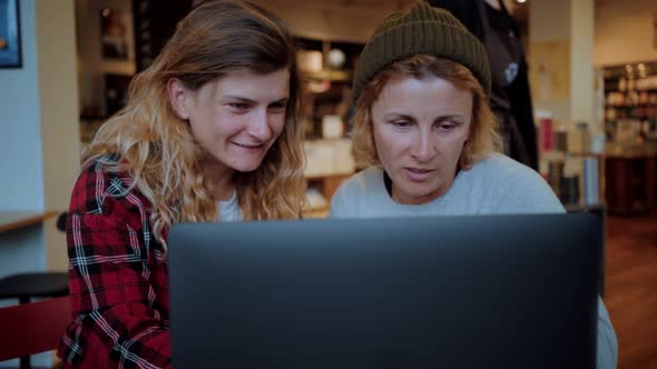 Two Women Work on Laptop in Cafe or Coworking alt