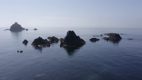 Calm water and misty coastal rock islets of South Ireland's Celtic Sea alt