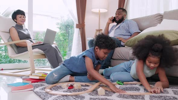 Funny small kids son and black parent having fun racing on floor at home in living room