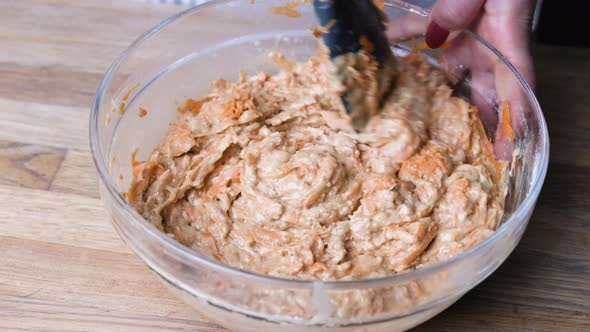 Hands Mixing Ingredients For Carrot Cake Baking In A Glass Bowl. close up, orbiting shot alt