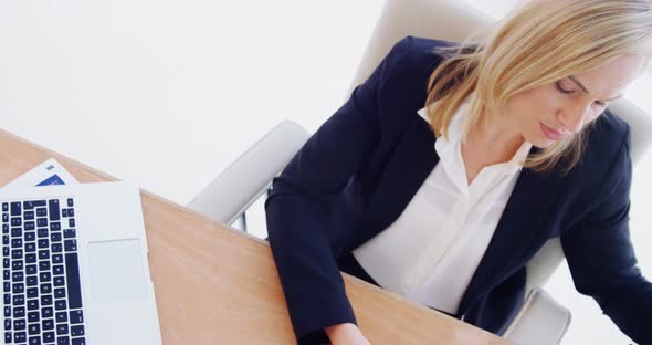 Businesswoman working over laptop at her desk alt