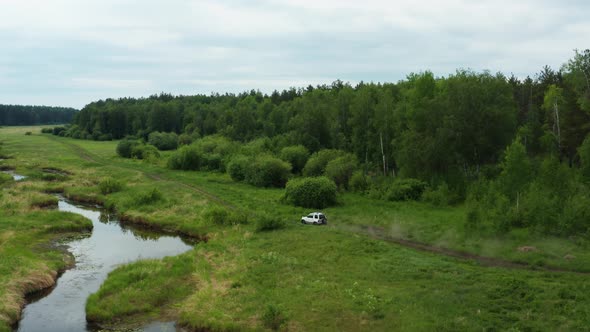 Aerial View of a Car Driving in Nature Near the River alt