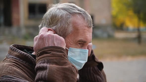 Close Up Portrait Elderly Man Puts a Medical Mask on His Face