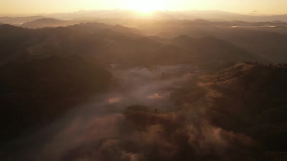 4K Aerial view from drone over mountains fog. Golden scenery at sunrise alt
