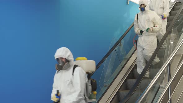 Disinfection Service on Escalator in the Building Team of Sanitation Workers in Suit Using Pressure alt