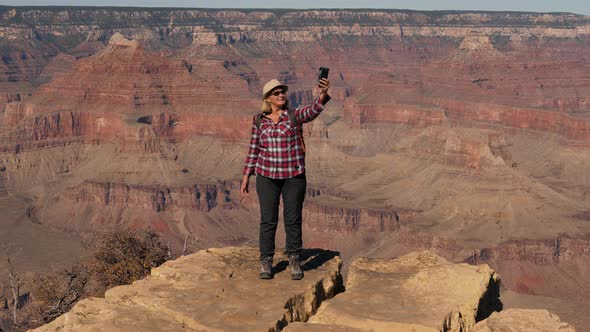 Hiker Woman Takes Selfie On Her Phone Standing On Edge Of Cliff In Grand Canyon alt
