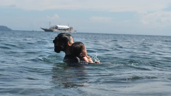 A Woman with a Small Child Swims in the Sea