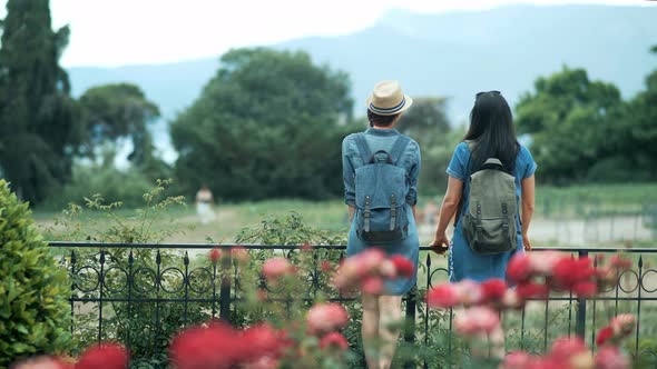 Two Tourist Women with Backpacks Enjoying the Beautiful View of the Mountains alt