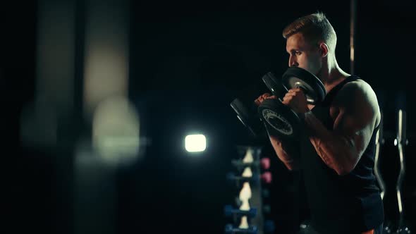A Muscular Man Doing Exercises Raises Dumbbells on Muscles of the Biceps, Heavy Weight. Hard alt