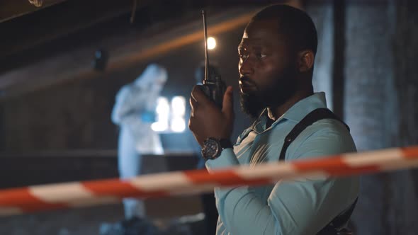 African Policeman in Talking on Radio Set at Crime Scene alt