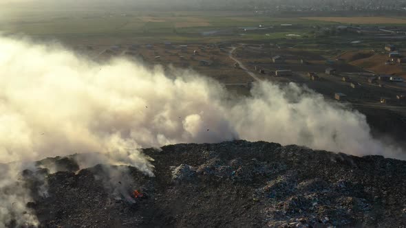 Aerial view of burning garbage pile in trash dump or landfill alt