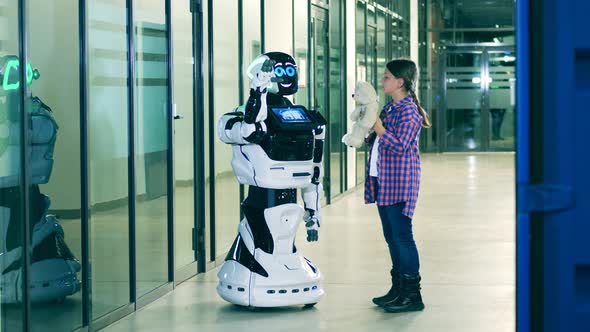 Young Girl Is Showing a Teddybear To a Cheerful Robot Modern Droid Friendly Cyborg alt