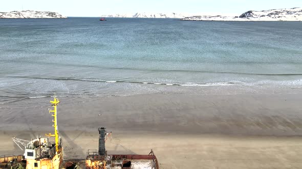 Aerial Top View of Old Wrecked Fishing Ships Drowned at the Sea Shore in Snowy Winter Season alt